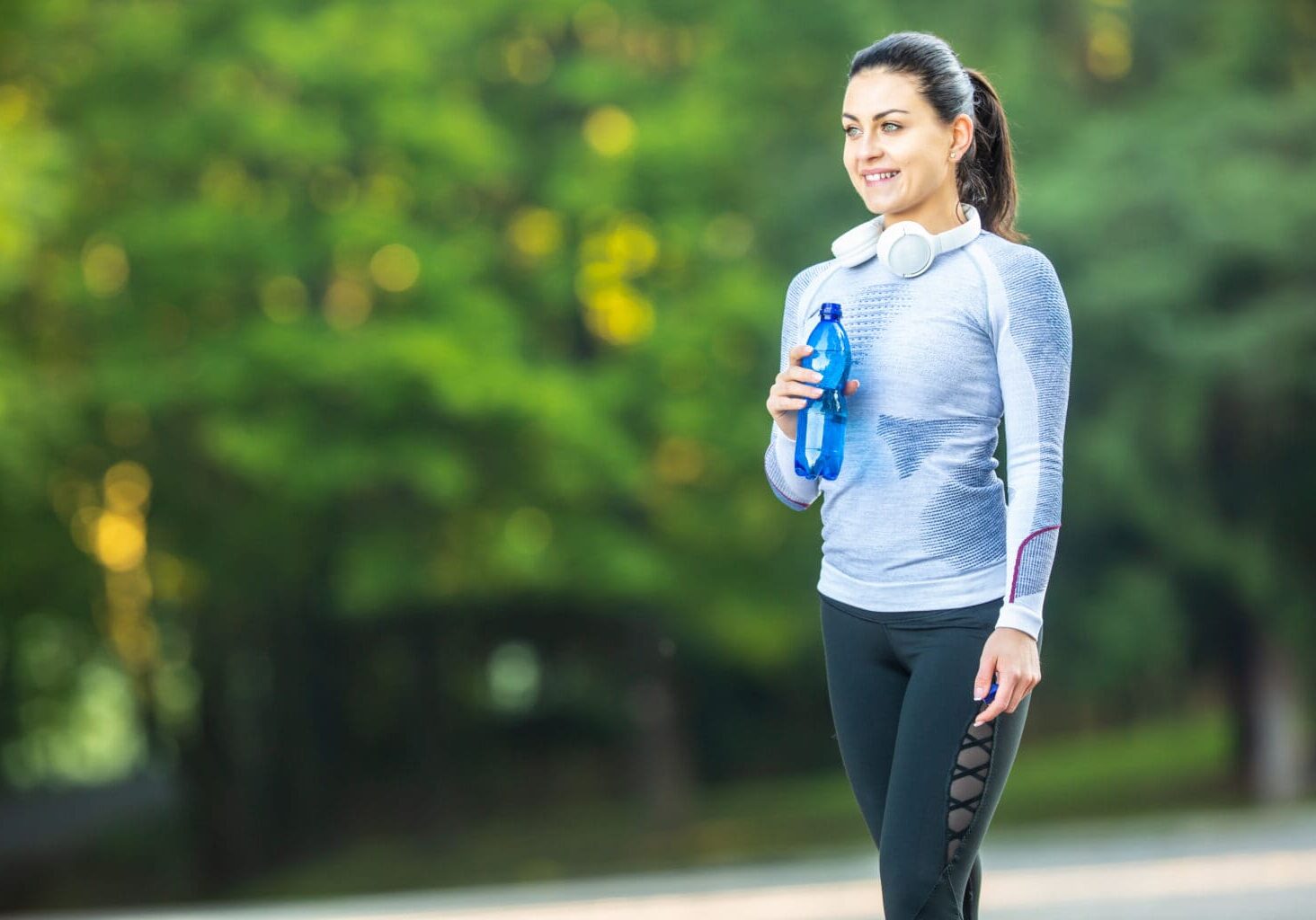 Young female athlete drinks water after training.